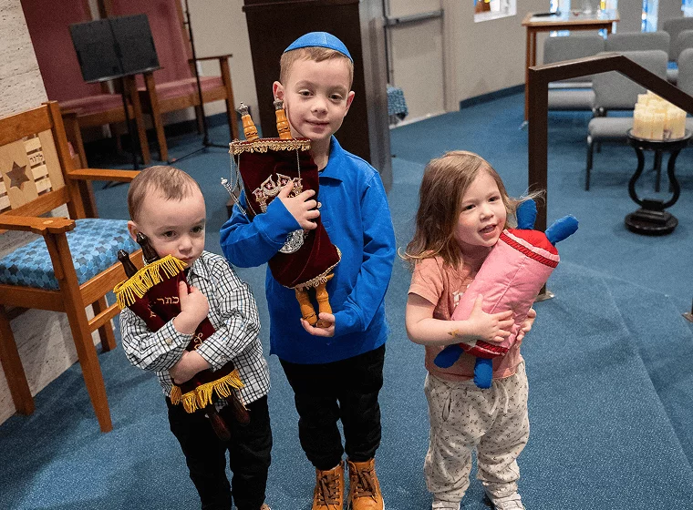 kids posing with plush torahs