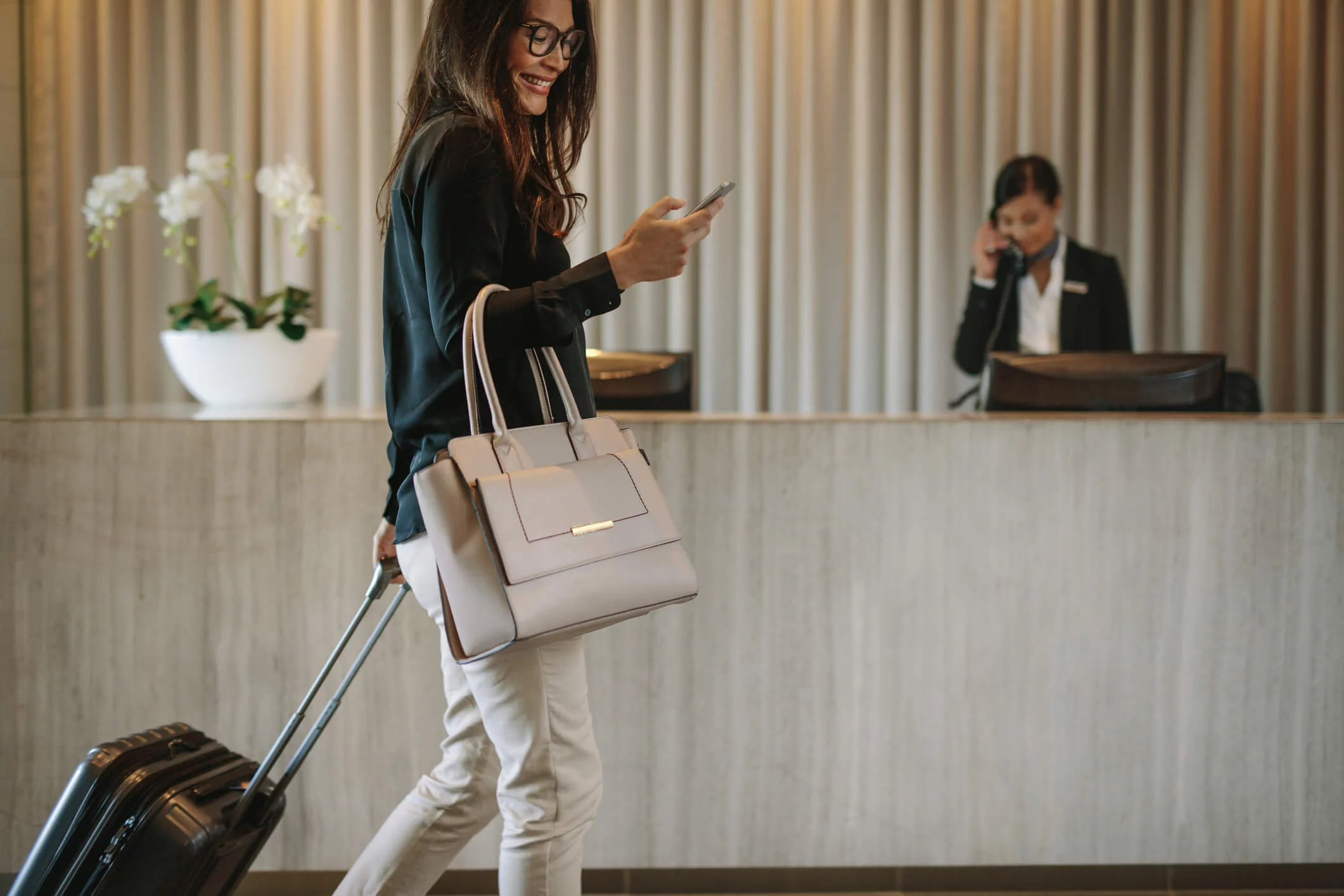 Hotel guest with luggage using a smartphone before scheduled transportation.