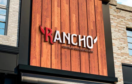 Design de logo e fachada 3D para o "Rancho Carnes e Conveniência", exibindo o letreiro e a identidade visual da marca em madeira.