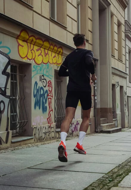 Pessoa correndo em uma rua de cidade, praticando corrida urbana. Imagem para site de fitness ou design de web site.