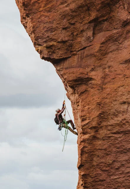Homem escalando uma rocha grande, mostrando esporte de escalada. Foto para portfólio de web designer focado em esportes radicais.