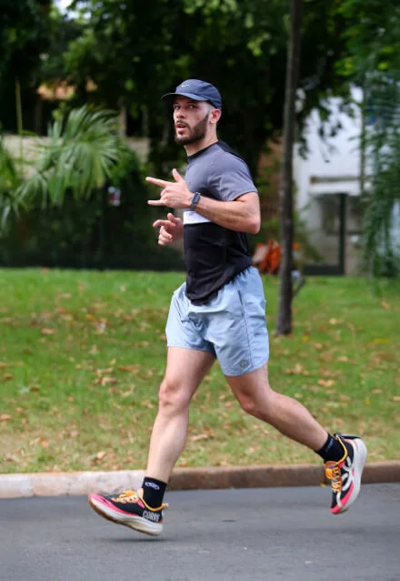 Atleta correndo em um parque com árvores, usando vestuário esportivo. Imagem para web design de site de maratonista ou corrida.
