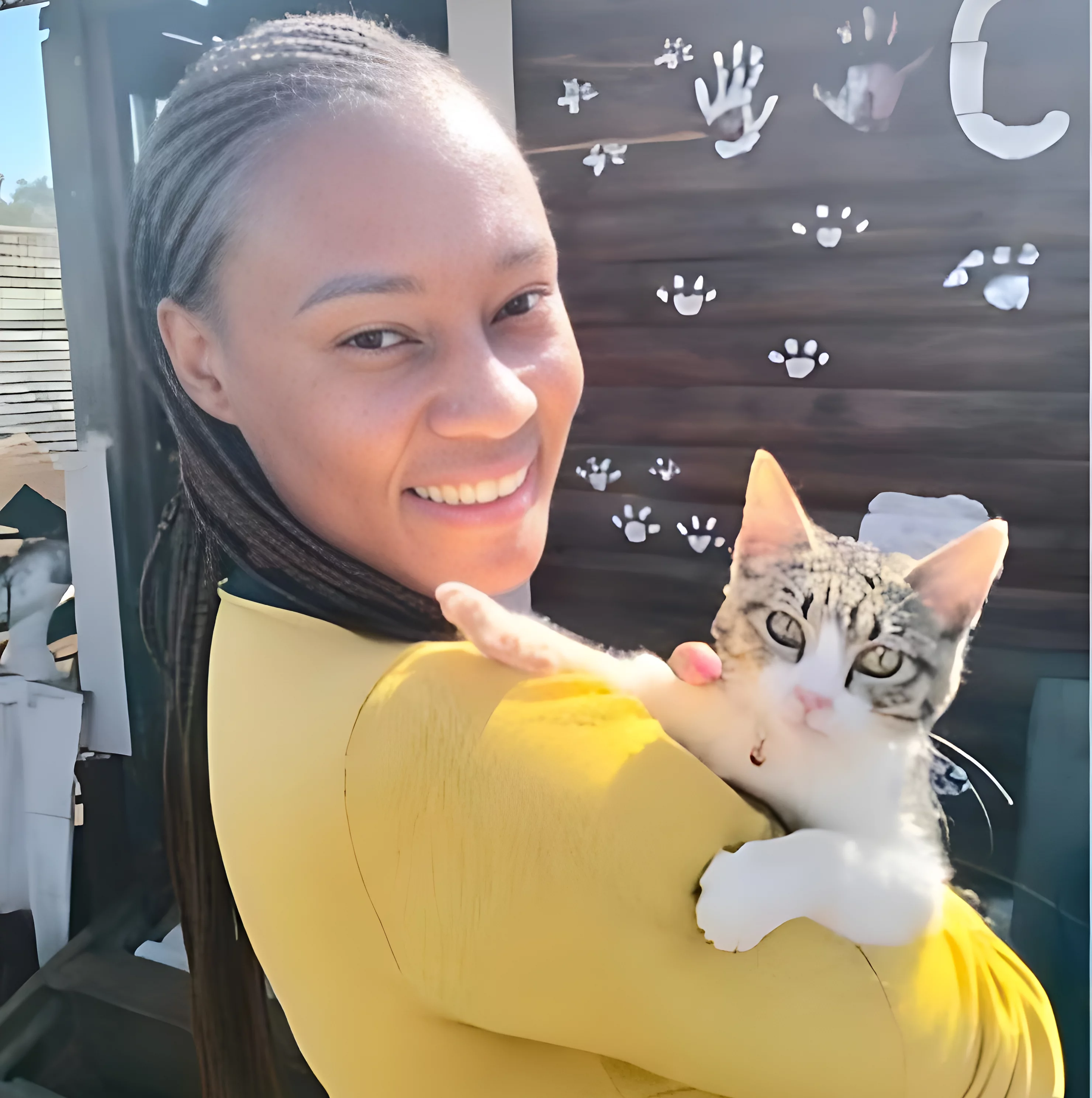 Adoption eight: Cat. Another young woman adopted a cat. The cat is still young but not a kitten anymore. The cat is also a Tabby cat with a white belly. The woman in the picture is very happy with the cat and is holding it in her arms while smiling into the camera.