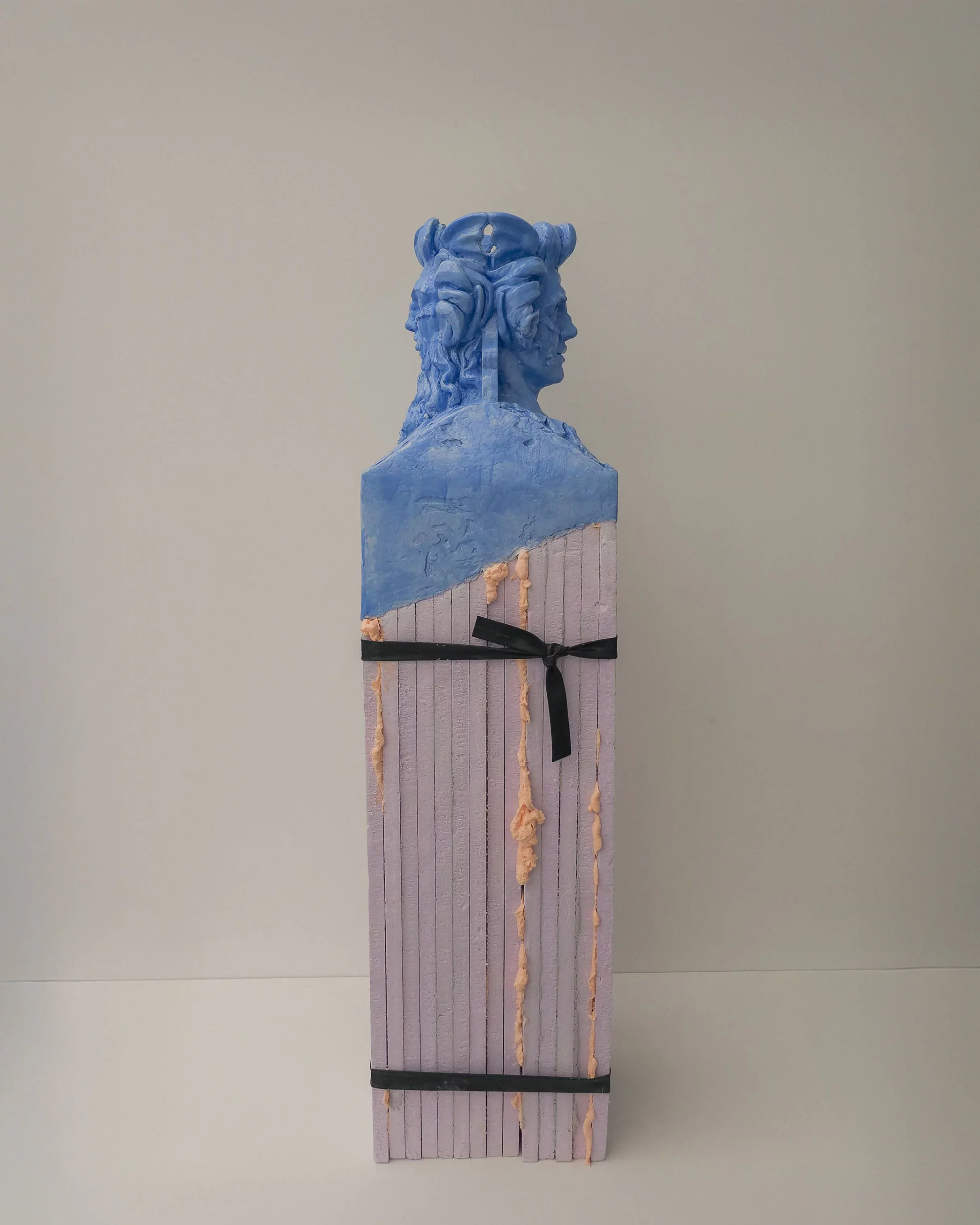"Confluence" (2026) by Grigorios Ilaridis. A double herm sculpture featuring an ultramarine blue silicone mythological bust on a pink XPS pedestal. The mixed-media work combines classical references with contemporary materials and collage-inspired textures.