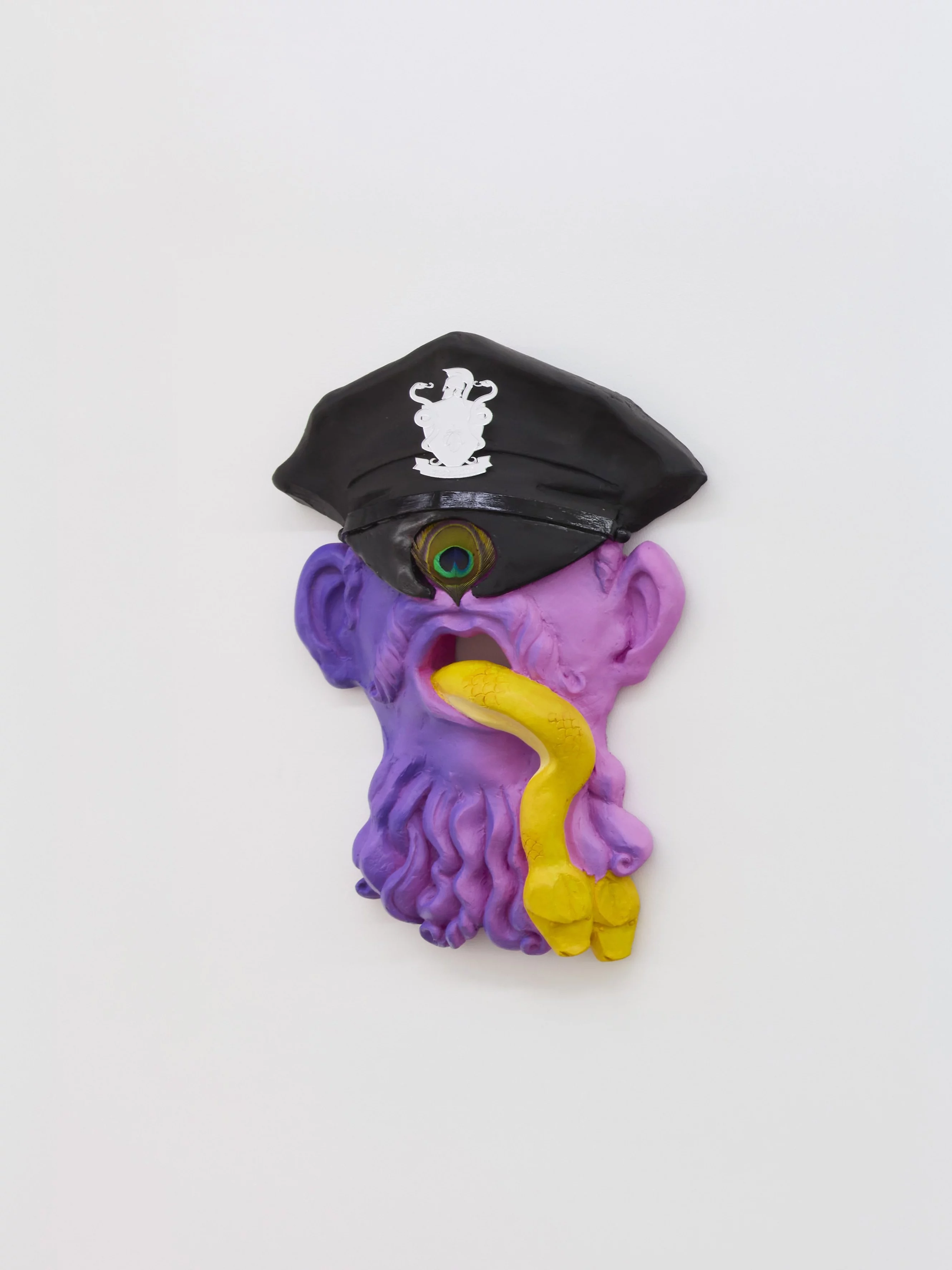 "Oral Tradition I," acrylic resin mask sculpture by emerging artist Grigorios Ilaridis at Base-Alpha Gallery in Antwerp. This magenta mask with a purple shadow portrays a cyclops figure with a peacock feather for an eye, wearing a black police cap with a mirrorplexi Greek-style heraldic crest. A yellow snake emerges from the mouth, splitting in two at the end of the beard. Made of acrylic, resin, and plexiglass. Dimensions: 60 x 40 x 11 cm.