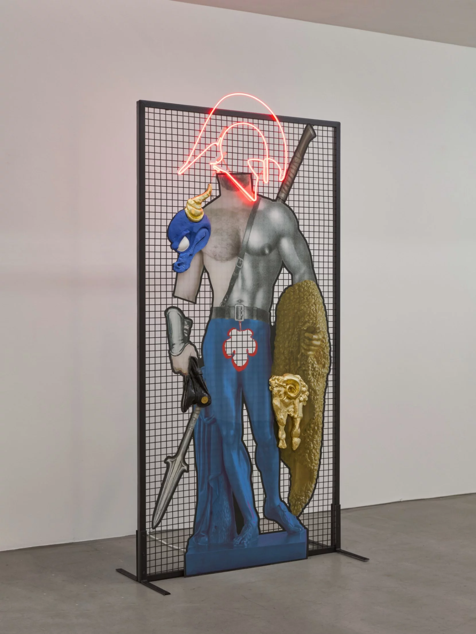 "Spartan Spoils," a 3D collage mixed-media sculpture by emerging antwerp sculptor Grigorios Ilaridis at Base-Alpha Gallery in Antwerp. This artwork features a bare-chested warrior figure with a red neon Spartan helmet, holding a spear. Three elements protrude the acrylic collage: a blue dragon head with a golden horn on the right shoulder, a black police cap held in the right hand, and a gold-leafed ram’s head with a golden fleece on the left elbow. The warrior’s legs are painted blue, resembling ballet tights. Materials include acrylic, resin, metal, and neon. Dimensions: 190 x 95 x 10 cm.