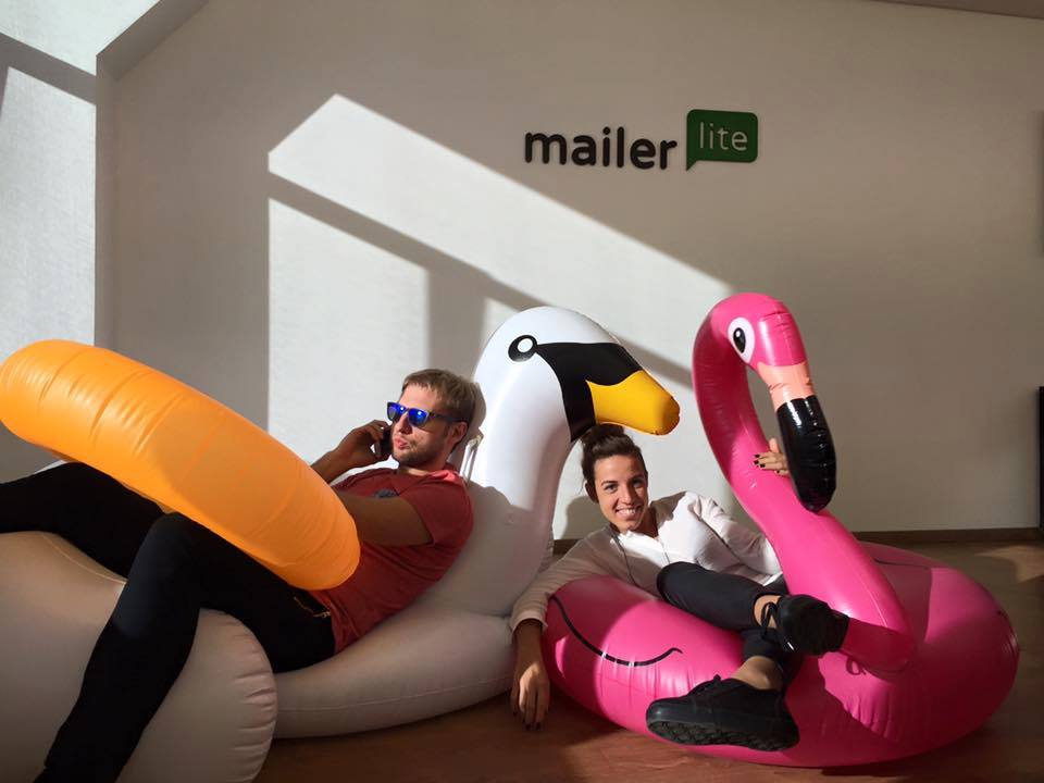 CEO Ignas and Hiring Manager Santa are sitting on giant inflatable birds with MailerLite logo on the wall behind them.